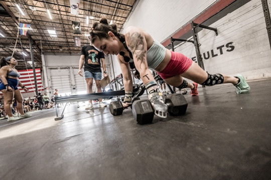 Athlete doing a push-up between dumbbells at a CrossFit competition